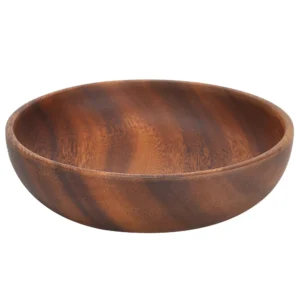 Organic shape acacia bowl holding a vibrant green side salad on a modern minimalist dining table