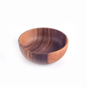 Dark acacia salad bowl filled with fresh garden greens on a minimalist Japanese style dining table